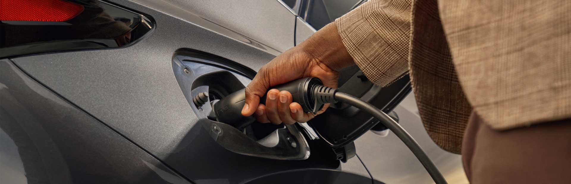 Close-up of a man's hand charging the Lexus NX 450h+.