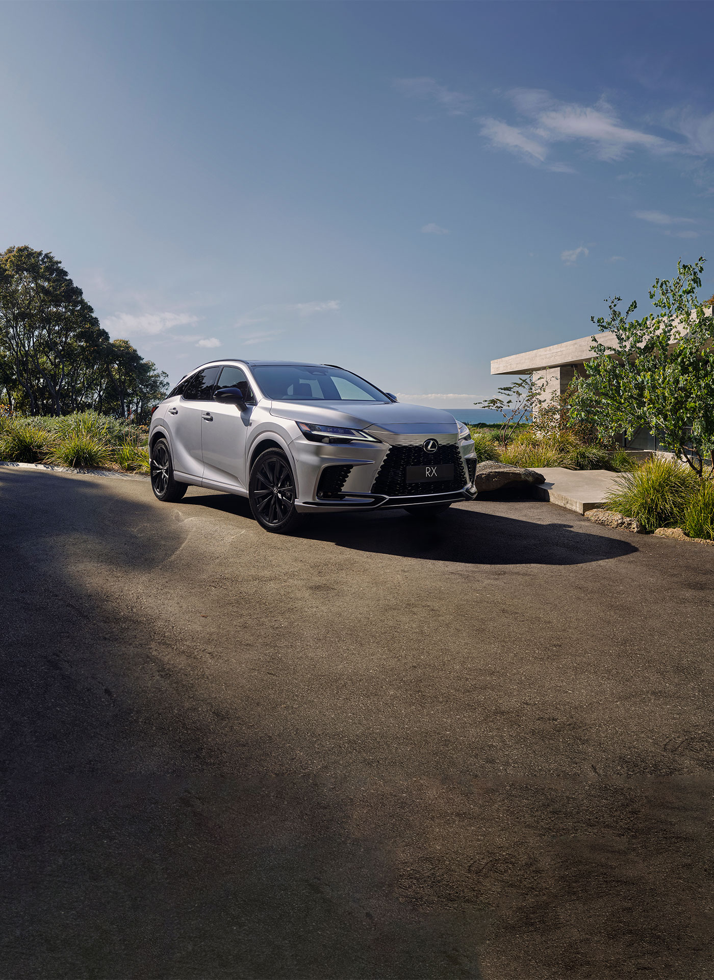 Two 2023 Lexus RX Vehicles are parked on a driveway in front of a luxury house.